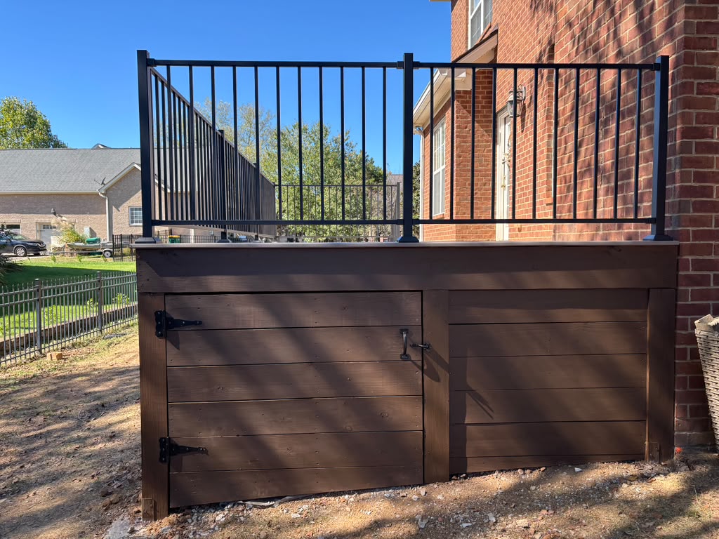 Wood-clad deck with storage access doors and black railing