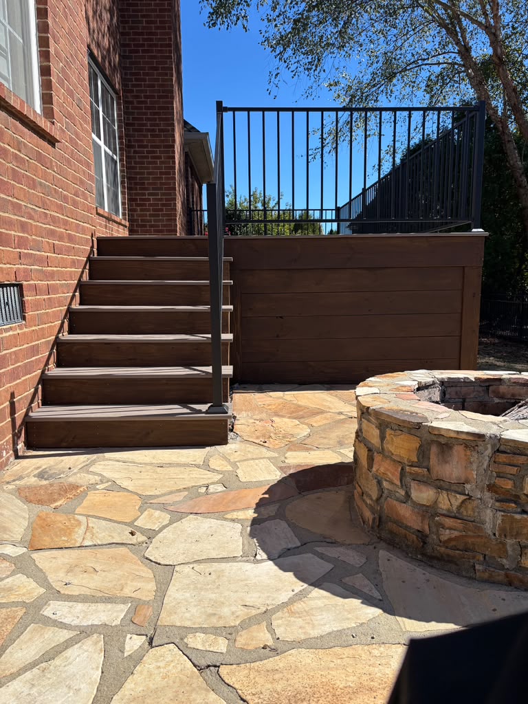 Deck staircase meeting a stone patio beside a fire pit